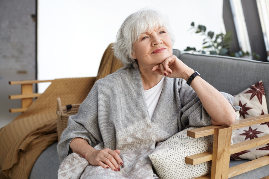 lovely-middle-aged-grey-haired-european-woman-with-dreamy-smile-eyes-full-wisdom-relaxing-home-alone-sitting-comfortable-couch